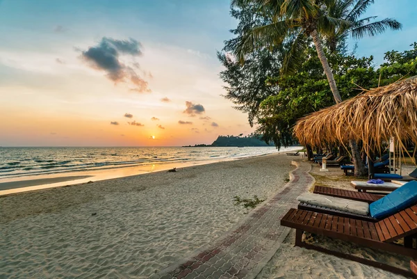 Houten stoelen en parasols op zand strand — Stockfoto