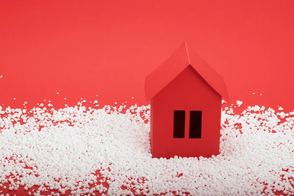 赤の背景に雪の中での紙の家 — ストック写真