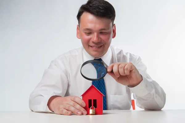 Man med ett förstoringsglas och papper house — Stockfoto