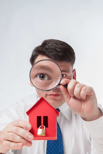 Man med ett förstoringsglas och papper house — Stockfoto