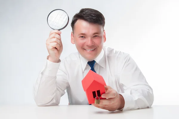 Man with a magnifying glass and paper house — Stock Photo, Image