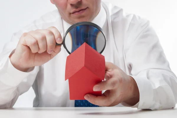 Man with a magnifying glass and paper house — Stock Photo, Image