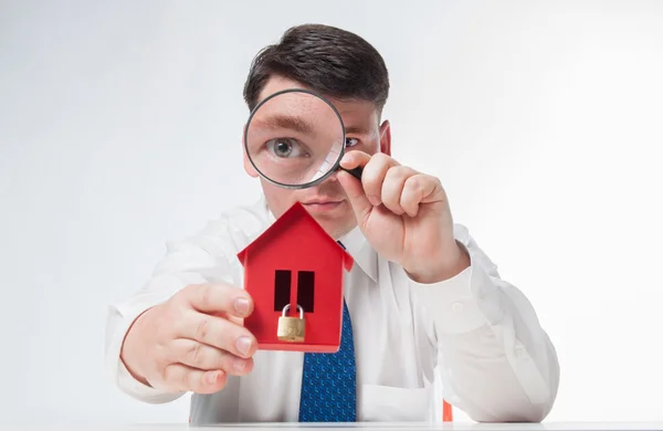 Man med ett förstoringsglas och papper house — Stockfoto