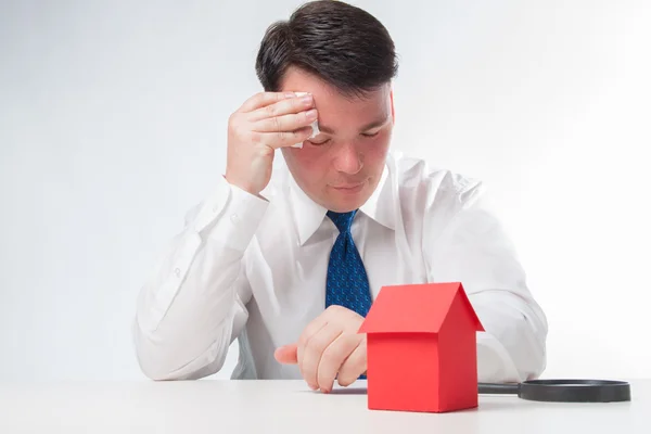 Verdrietig Man met een vergrootglas en papier huis — Stockfoto