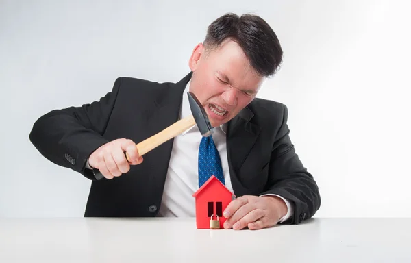 Homens irritados segurando martelo sobre casa de papel vermelho — Fotografia de Stock