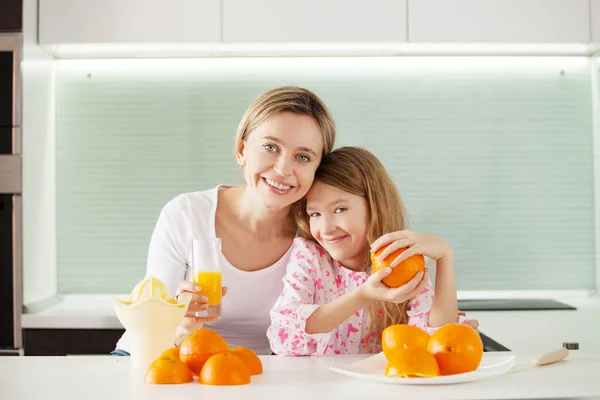 Mãe e filha fazem suco de laranja em um espremedor de frutas — Fotografia de Stock