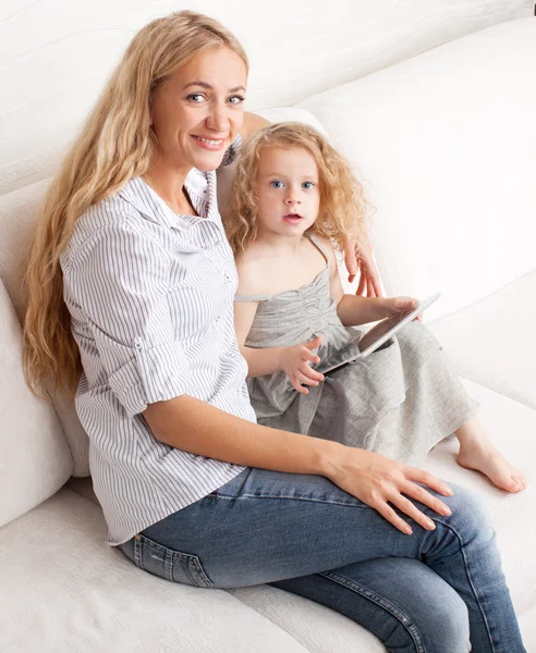 Madre e hija wiht tableta en el sofá — Foto de Stock