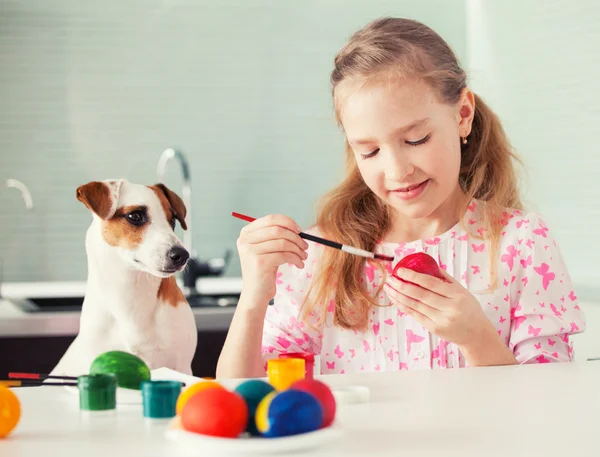 Chica con perro pintando huevos — Foto de Stock