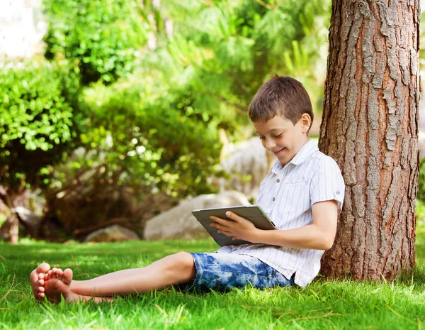 Niño en la hierba con la tableta — Foto de Stock