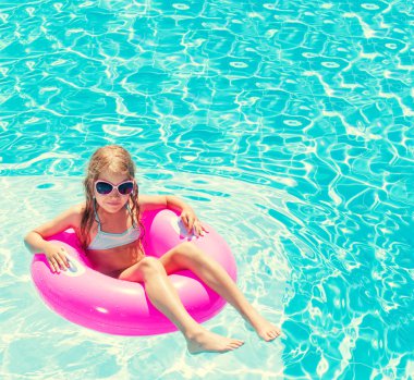 Yüzme havuzunda şişme yüzük takan kız.