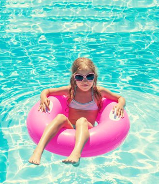 Yüzme havuzunda şişme yüzük takan kız.