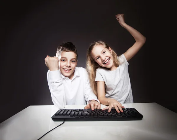 Leuke kinderen, een computer kijken — Stockfoto