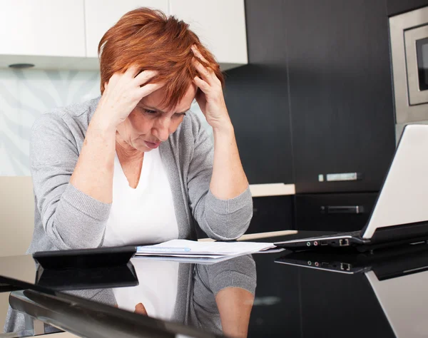 Oudere vrouw sorteren door middel van haar oude ontvangsten — Stockfoto