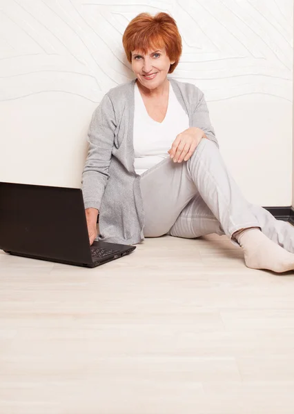 Женщина сидит на полу с ноутбуком — стоковое фото