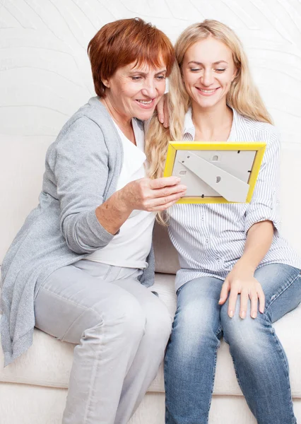 Mãe com filha olhando para moldura da foto — Fotografia de Stock