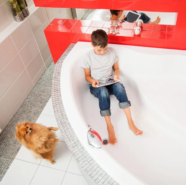 Boy hiding in the bathroom, playing in tablet — Stock Photo, Image