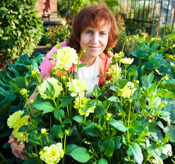 Woman in the garden cares for flowers — Stock Photo, Image