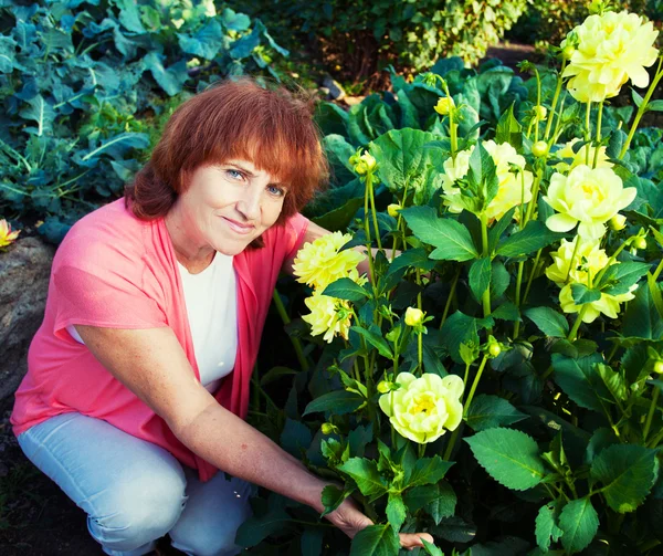 Kvinna i trädgården bryr sig för blommor — Stockfoto