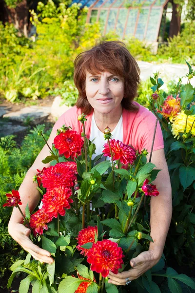 Vrouw in de tuin zorgen voor bloemen — Stockfoto