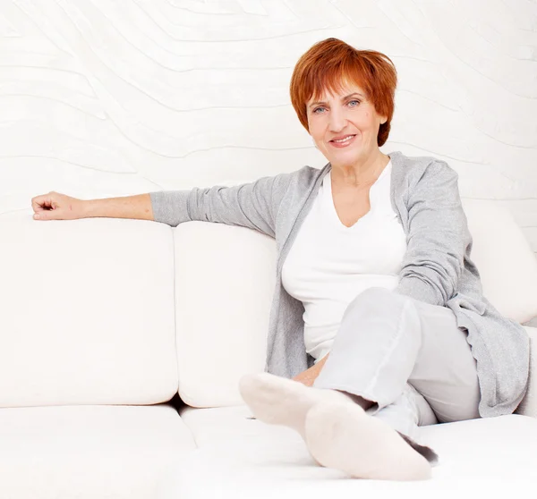 Happy mature woman on sofa — Stock Photo, Image