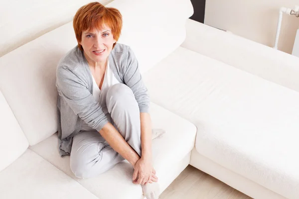 Happy mature woman on sofa — Stock Photo, Image