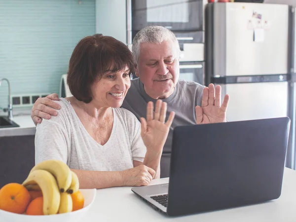 Casal de idosos olhando para o computador na cozinha — Fotografia de Stock