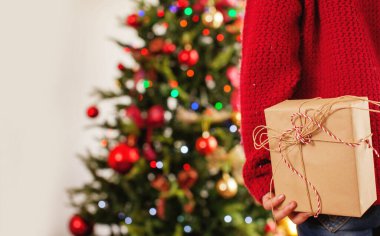 Arkasında bir hediyeyle Noel ağacının yanındaki çocuk.