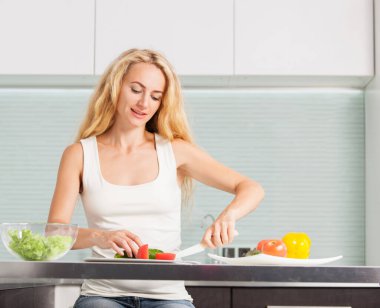 Genç bayan mutfakta sebze salatası hazırlıyor.