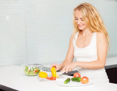 Genç bayan mutfakta sebze salatası hazırlıyor.