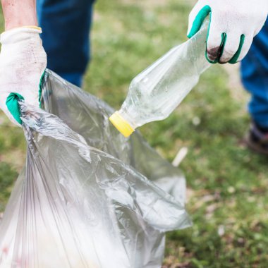 Adam çöp ve plastik şişe topluyor. Ormandaki çöpleri temizleyen bir adam küresel çevre kirliliği sorunu