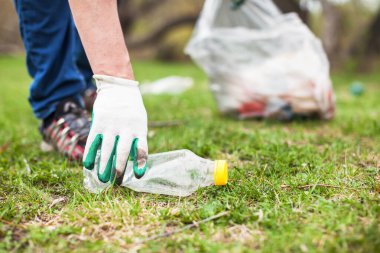 Adam çöp ve plastik şişe topluyor. Ormandaki çöpleri temizleyen bir adam küresel çevre kirliliği sorunu