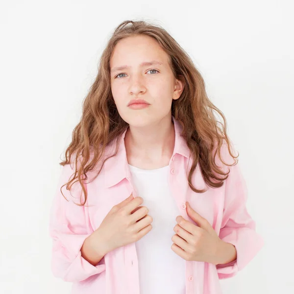 自然な若い女の子は カメラで頭を回し 明るく見て ピンクのシャツの白い背景に立っている 慎重なティーン学生の肖像 スタジオショット — ストック写真