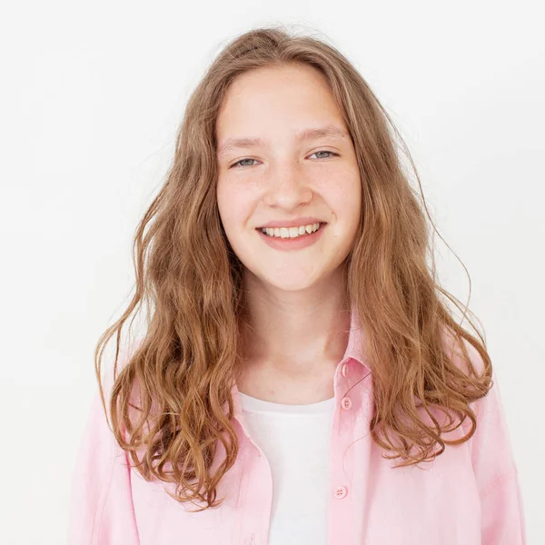 幸せな笑顔で自然な若い女の子は カメラで頭を回し 明るく見て ピンクのシャツの白い背景に対して立っている 楽しいですティーン学生スタジオショットの肖像 — ストック写真