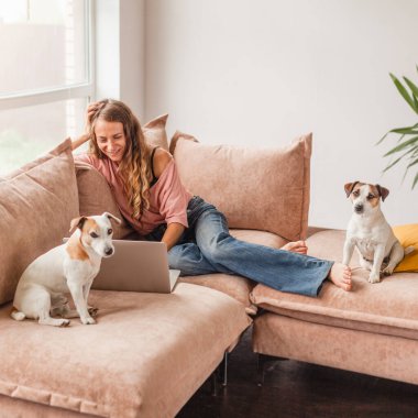 Genç bayan arkadaşlarıyla uzaktan konuşmak için bilgisayarını kullanıyor. Komik kız evde köpekli bir kadın olarak eğleniyor.