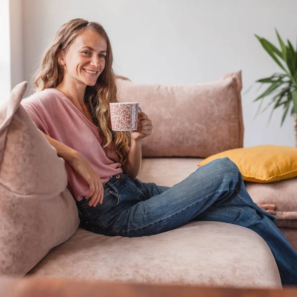 安详祥和的中年妇女休息一下 在沙发上喝杯热茶休息一下 满足迷人的快乐女士在沙发上喝咖啡和做白日梦 — 图库照片