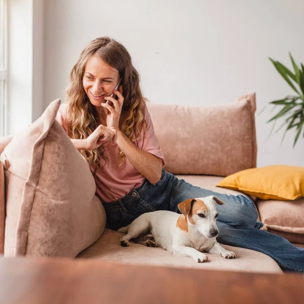 Glimlachende Vrouw Die Met Vrienden Smartphone Praat Terwijl Thuis Bank — Stockfoto