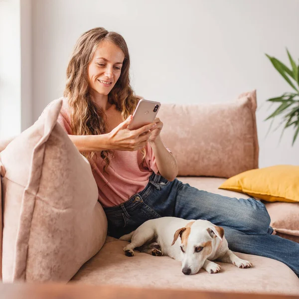 Lachende Vrouw Ontspannen Zitten Bank Thuis Met Hond Hold Mobiele — Stockfoto