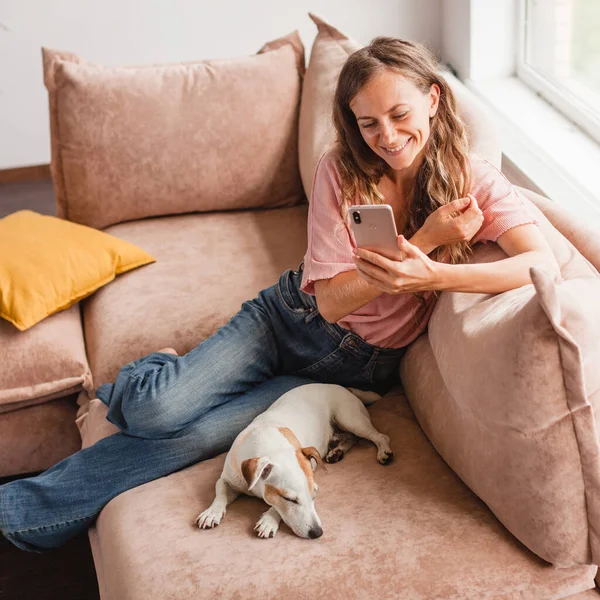Lachende Jonge Vrouw Thuis Met Behulp Van Een Moderne Smartphone — Stockfoto