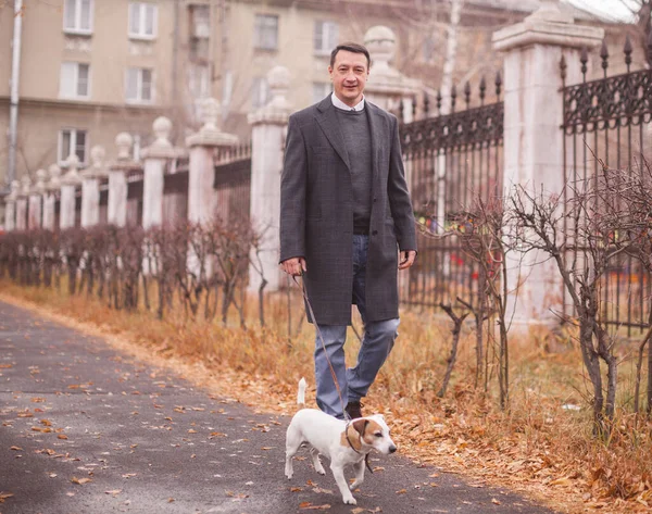 Adam köpeğiyle yürüyor. Sokaktaki evcil hayvanlı adam.