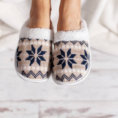 Terlik bir ahşap zemin çerçevede kadın bacaklar. Rahat, sıcak ve rahat terlik ayakları üzerinde