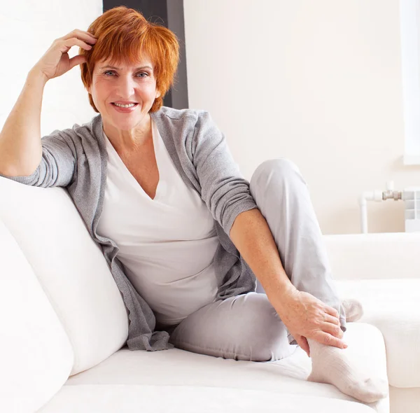 Gelukkig volwassen vrouw op sofa — Stockfoto