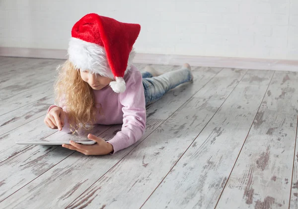 Child in christmas hat with tablet — Stock Photo, Image