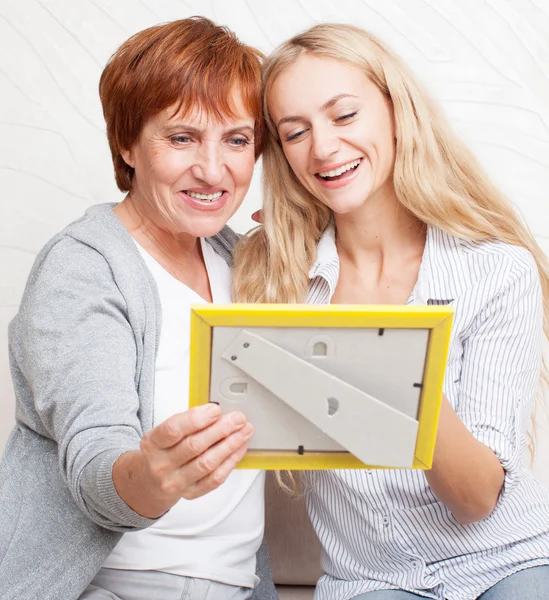 Mor med dotter tittar på fotoram Stockbild