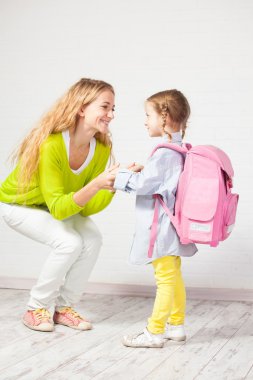 Anne kızının okula hazırlanmasına yardım ediyor.