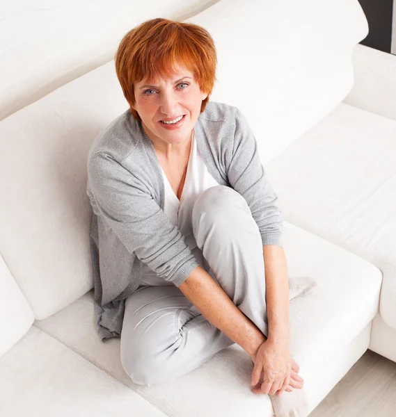 Happy mature woman on sofa — Stock Photo, Image