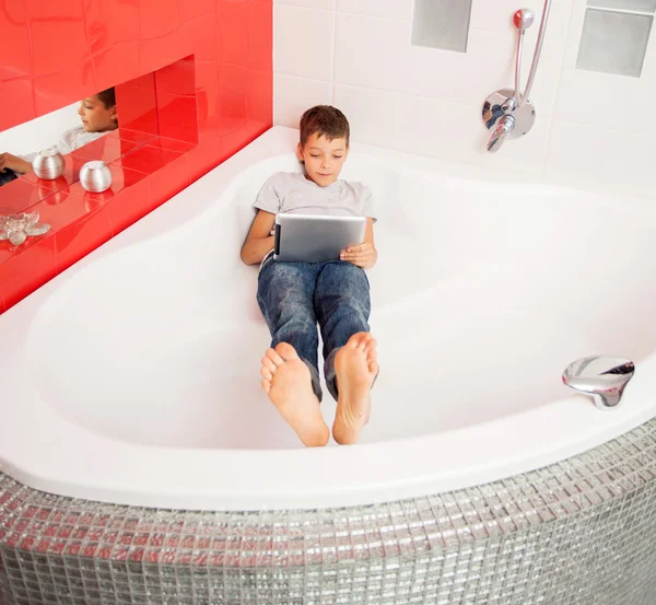 Niño escondido en el baño, jugando en la tableta — Foto de Stock