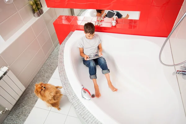 Jongen verbergen in de badkamer, spelen in Tablet PC — Stockfoto