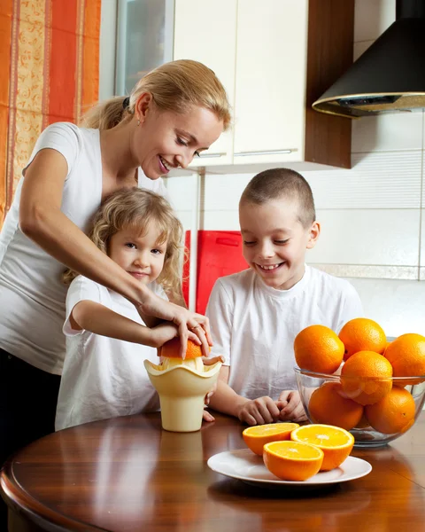 Moeder met kinderen geperst sinaasappelsap — Stockfoto