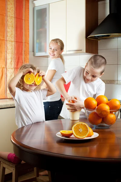 Matka s dětmi vymačkaná pomerančová šťáva — Stock fotografie