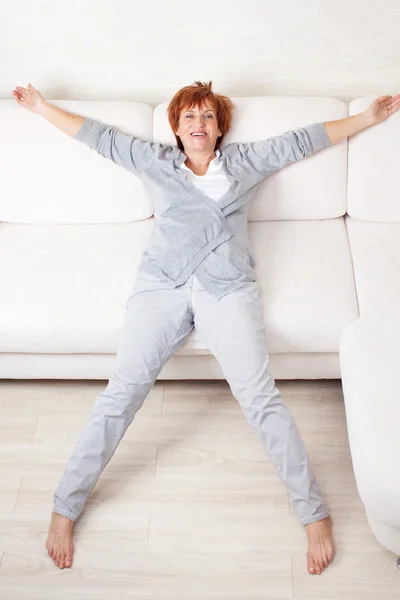 Mulher madura feliz no sofá — Fotografia de Stock